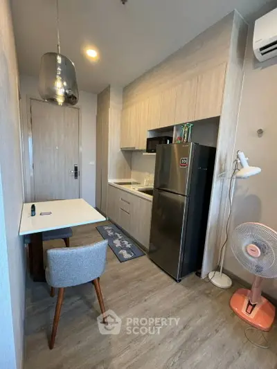 Modern compact kitchen with sleek appliances and stylish dining area in a cozy apartment.