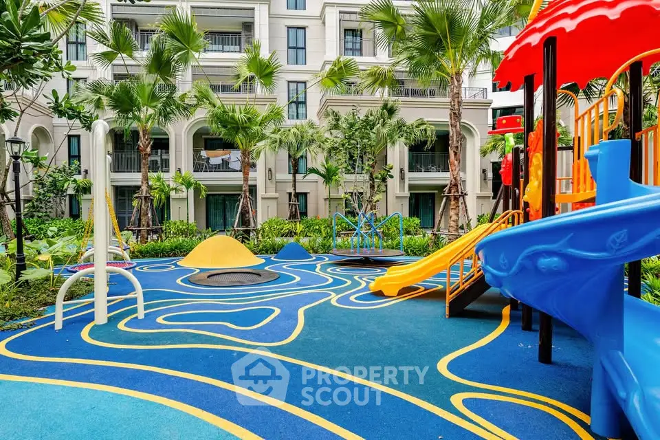 Vibrant residential playground with colorful slides and lush greenery in modern apartment complex.