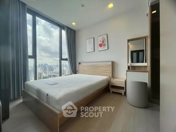 Modern bedroom with city view, featuring large windows and stylish decor in a high-rise apartment.