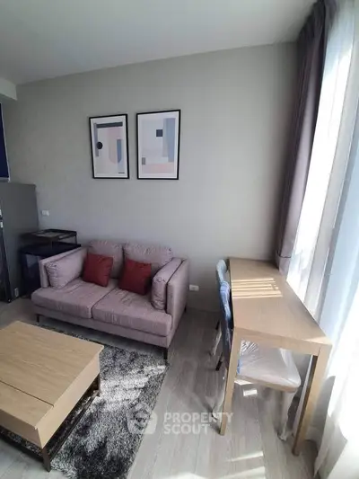 Modern living room with stylish decor, cozy sofa, and natural light from large windows.