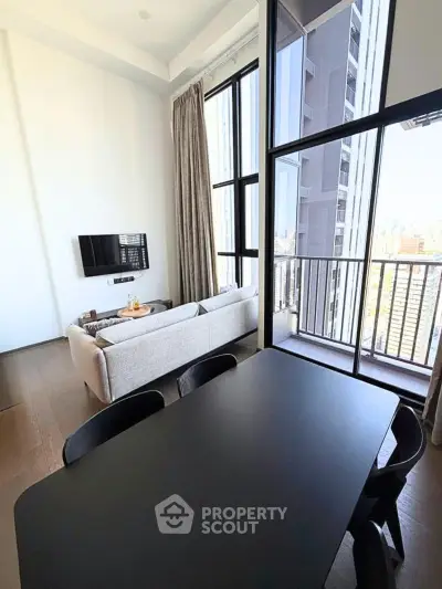 Modern living room with floor-to-ceiling windows and city view, featuring sleek furniture and elegant decor.