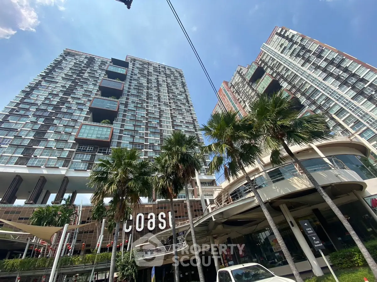 Modern high-rise buildings with palm trees and clear blue sky, showcasing urban living at its finest.