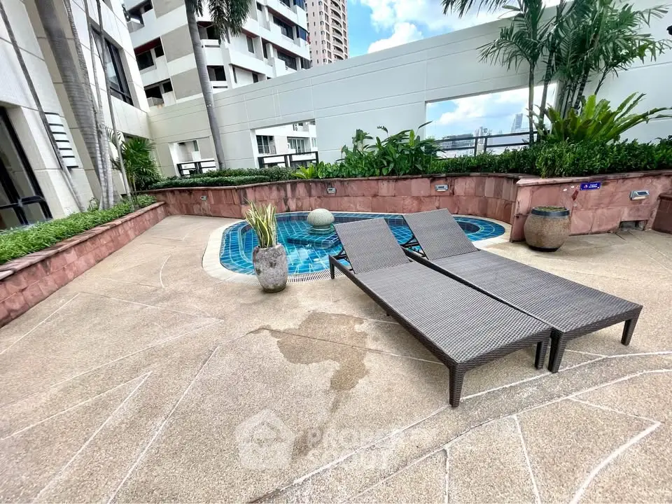 Luxurious rooftop pool area with stylish loungers and lush greenery in a modern high-rise building.