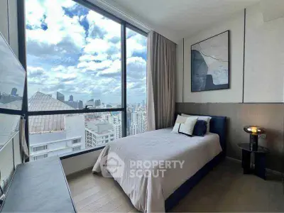 Modern bedroom with large windows offering stunning city views, featuring stylish decor and cozy ambiance.