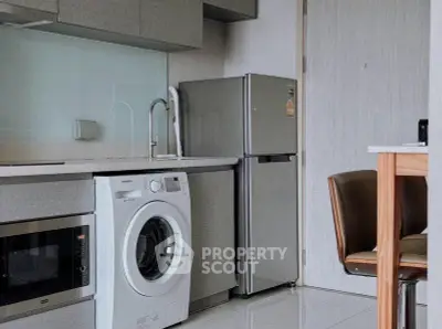 Modern kitchen with sleek appliances including washing machine and fridge, ideal for urban living.