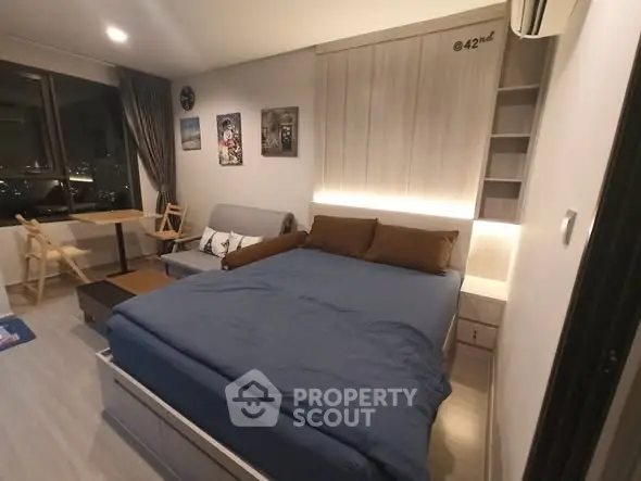 Modern studio apartment with cozy bed and city view, perfect for urban living.