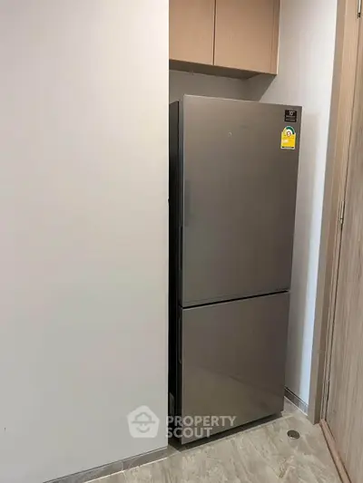 Modern kitchen with sleek stainless steel refrigerator in compact space.