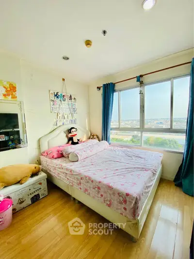 Charming bedroom with large window offering stunning city views, featuring cozy decor and ample natural light.