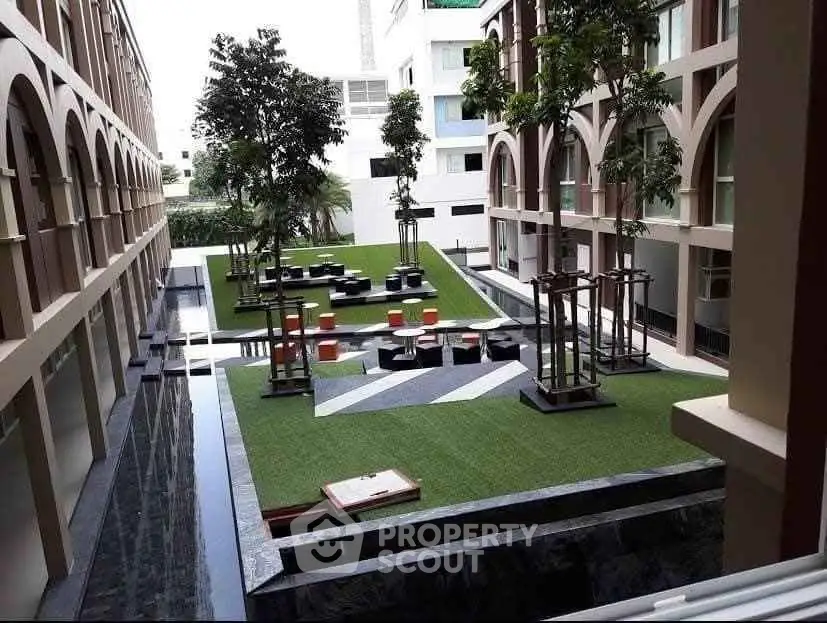 Modern building courtyard with lush greenery and stylish seating area