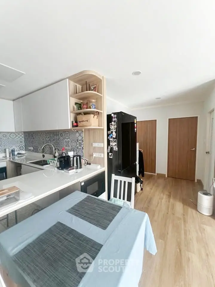 Modern kitchen with sleek cabinetry and open layout, featuring a stylish backsplash and wooden flooring.