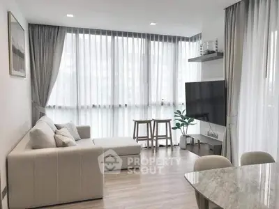Modern living room with large windows, stylish furniture, and natural light.