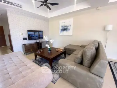Modern living room with stylish furniture and wall art, featuring a cozy seating area and flat-screen TV.