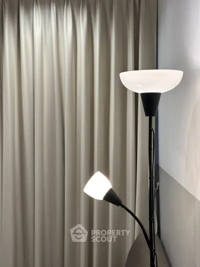 Elegant modern floor lamp with soft lighting against stylish curtains in cozy living room corner.