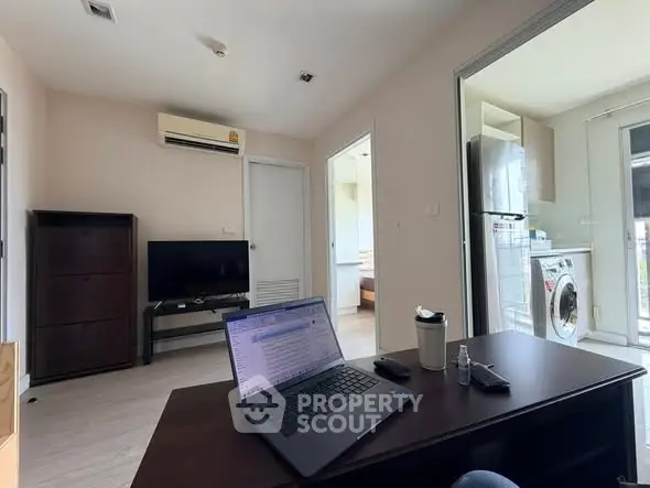 Modern living room with air conditioning, TV, and washing machine in a cozy apartment setting.