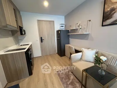 Modern studio apartment with stylish kitchen and cozy living area, featuring elegant decor and wooden flooring.