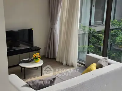 Bright living room with large windows and modern decor overlooking greenery.