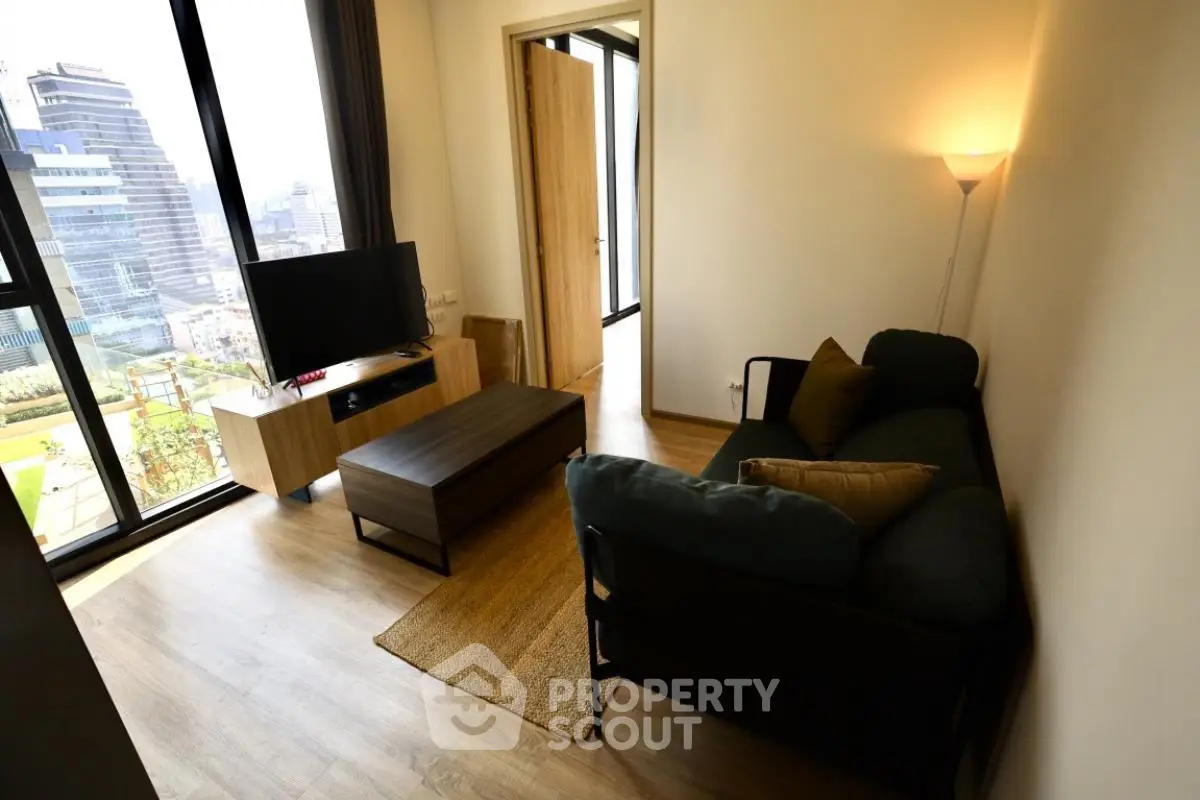 Modern living room with city view, featuring sleek furniture and natural light.