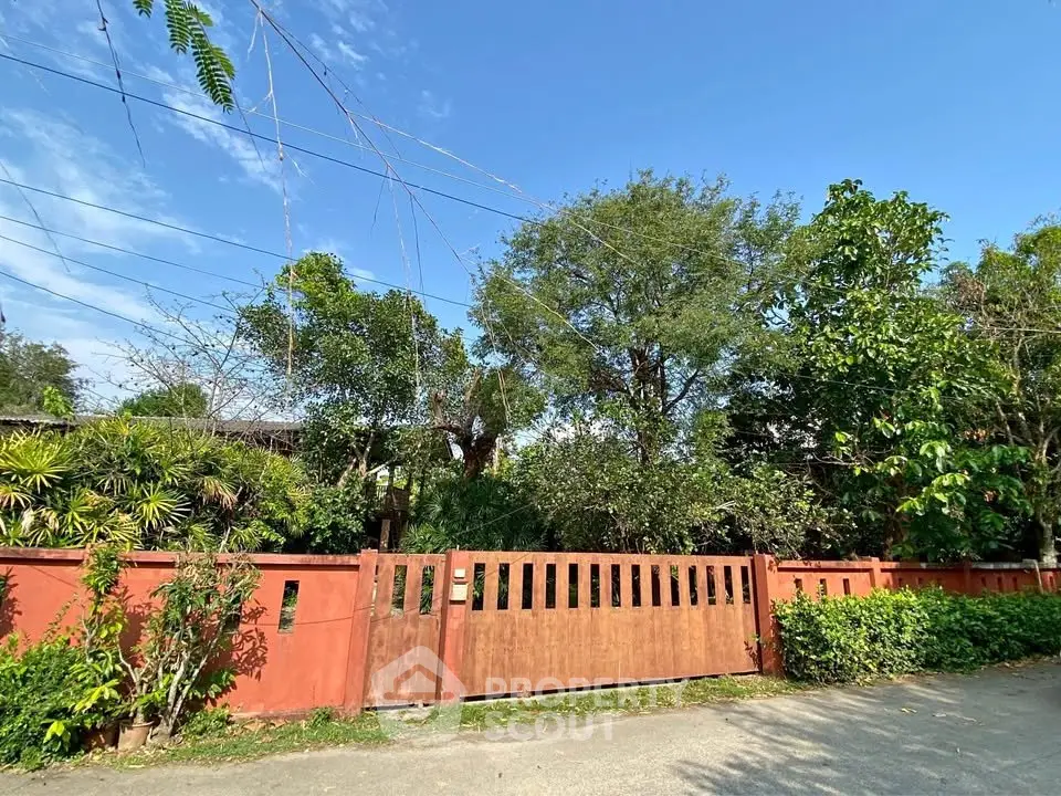 Charming property with lush greenery and a rustic wooden gate, perfect for nature lovers seeking tranquility.