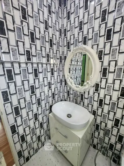 Chic modern bathroom with stylish black and white tile design and elegant round mirror.