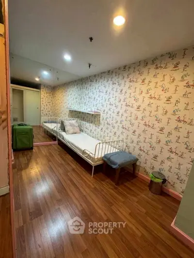 Charming bedroom with wooden flooring and playful wallpaper, featuring a cozy single bed and mirrored closet.