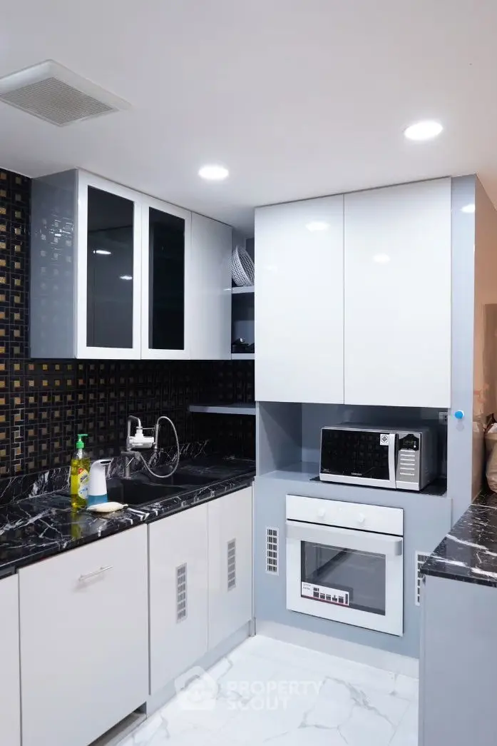 Modern kitchen with sleek cabinets, black marble countertops, and built-in appliances.