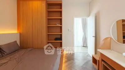 Modern bedroom with wooden accents and built-in shelving, featuring a cozy bed and stylish decor.