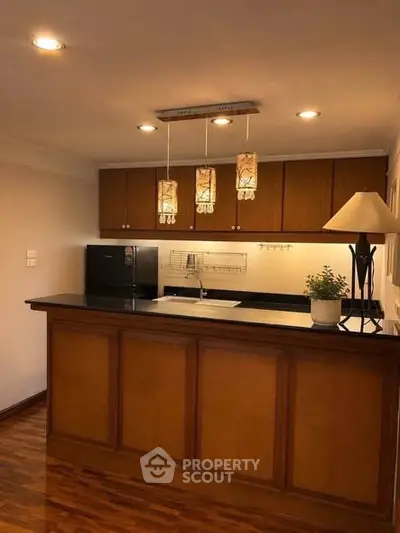 Charming kitchen with wooden cabinetry and modern lighting in cozy apartment