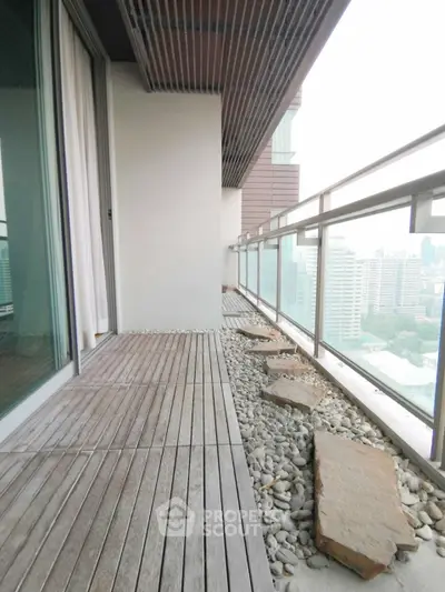 Spacious balcony with city view and modern design in high-rise apartment.