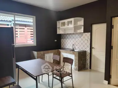 Modern kitchen with sleek design and dining area, featuring dark cabinetry and tiled backsplash.