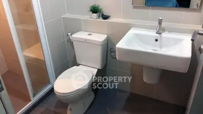 Modern bathroom with sleek fixtures and a compact design, featuring a shower and stylish sink.