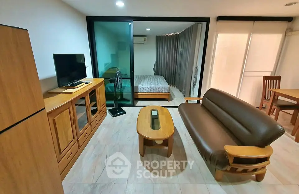 Modern studio apartment with cozy living area and bedroom separated by glass partition.