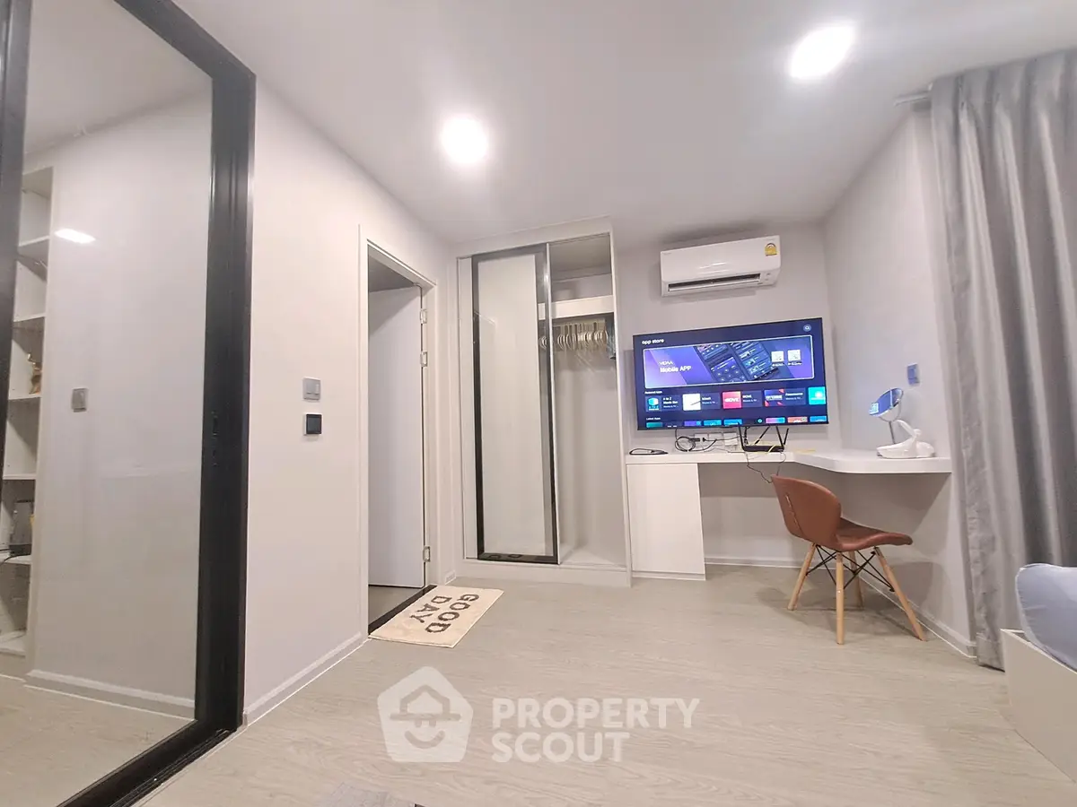 Modern living room with sleek design, featuring a wall-mounted TV, air conditioning, and stylish furniture.