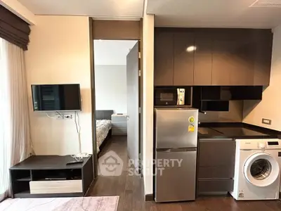 Modern apartment interior with compact kitchen and cozy living area, featuring a washing machine and sleek appliances.