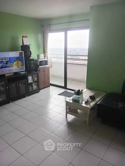 Spacious living room with balcony access and city view, perfect for relaxation and entertainment.