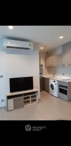 Modern apartment interior with TV, air conditioning, and kitchen appliances.