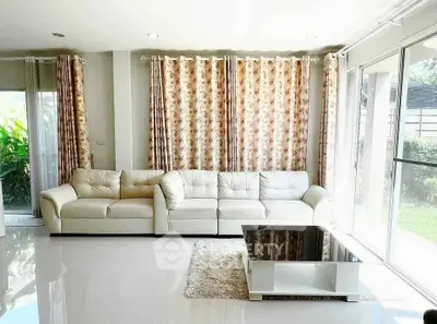 Spacious living room with elegant white sofa and large windows overlooking garden