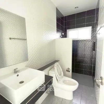 Modern bathroom with sleek black and white tiles, featuring a stylish sink and toilet.