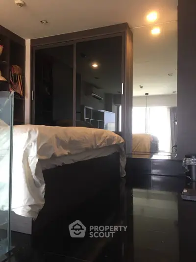 Modern bedroom with sleek design and mirrored wardrobe reflecting natural light.