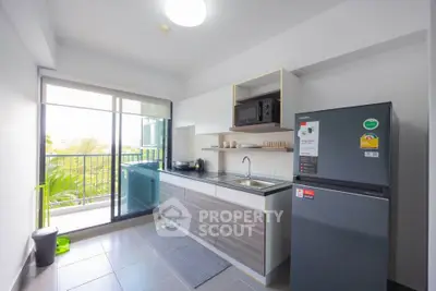 Modern kitchen with balcony access and sleek appliances in a bright apartment.