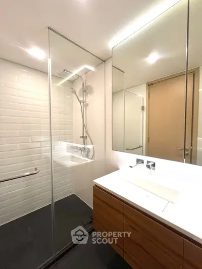 Modern bathroom with glass shower and sleek vanity in contemporary home.