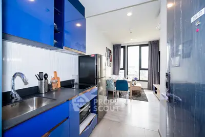 Modern open kitchen with blue cabinets and cozy living area in bright apartment