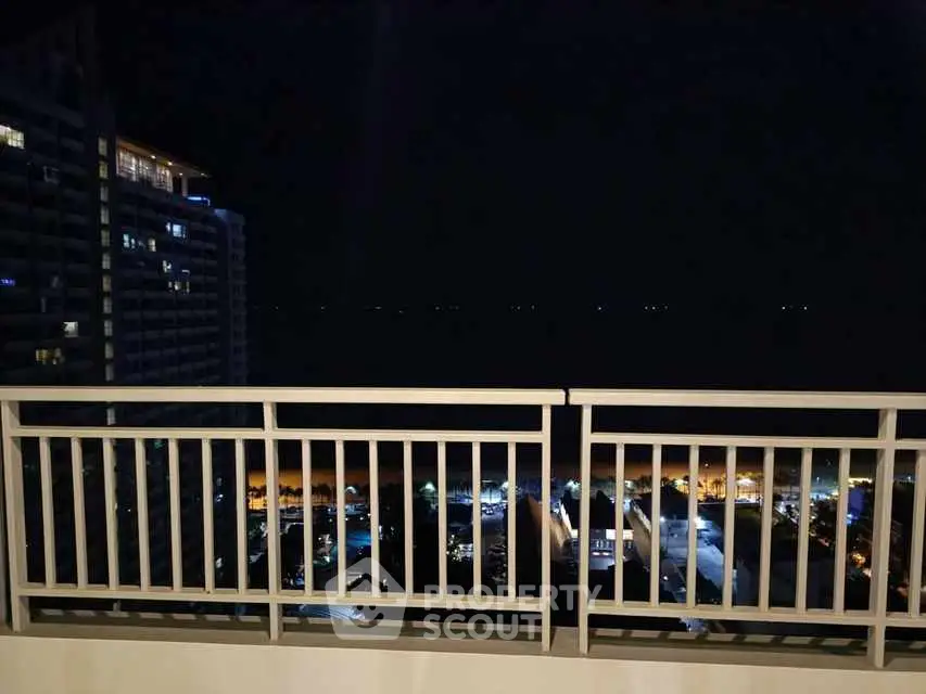 Stunning night view from a high-rise balcony overlooking city lights and distant horizon.