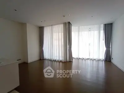 Spacious empty living room with large windows and elegant curtains