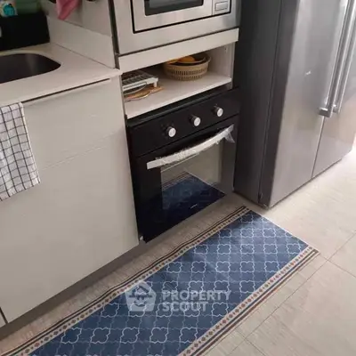 Modern kitchen with built-in oven and stainless steel fridge, featuring sleek cabinetry and stylish flooring.