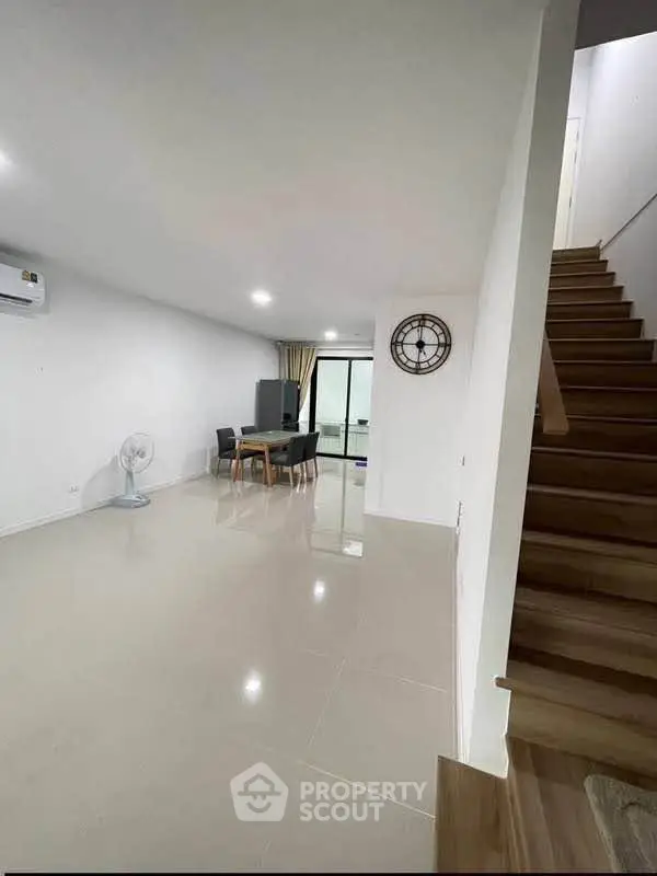 Spacious modern living room with dining area and staircase in a minimalist home.
