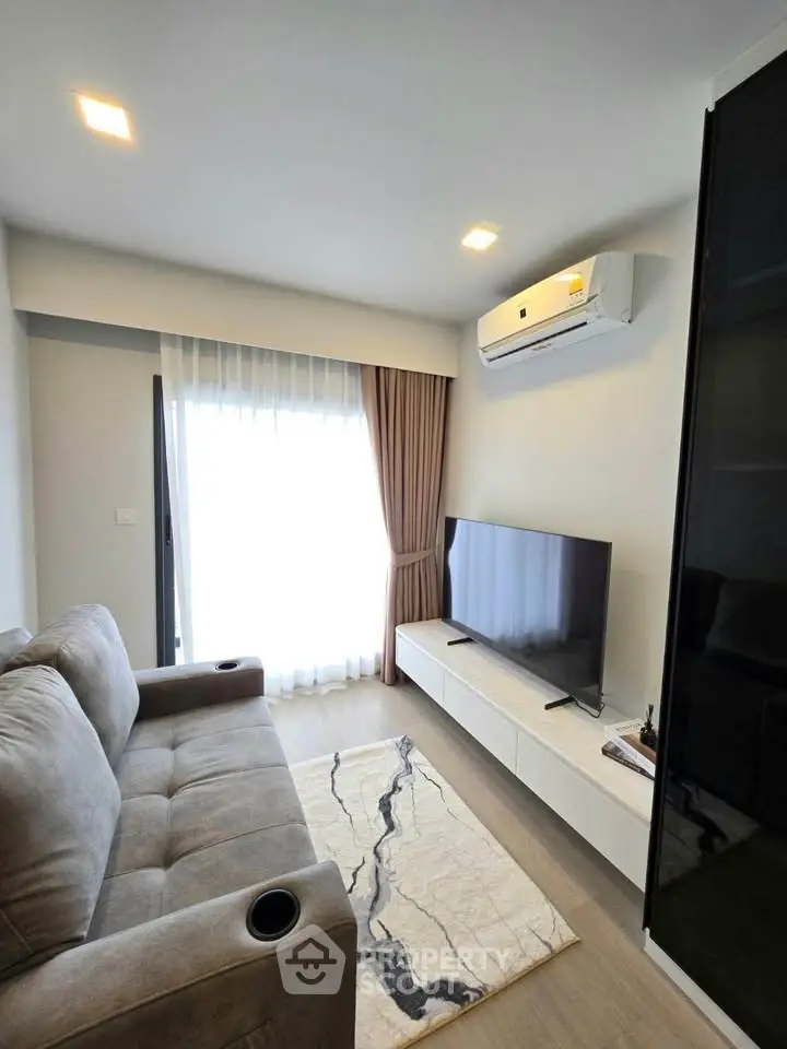 Modern living room with cozy sofa, sleek TV unit, and natural light from large window.