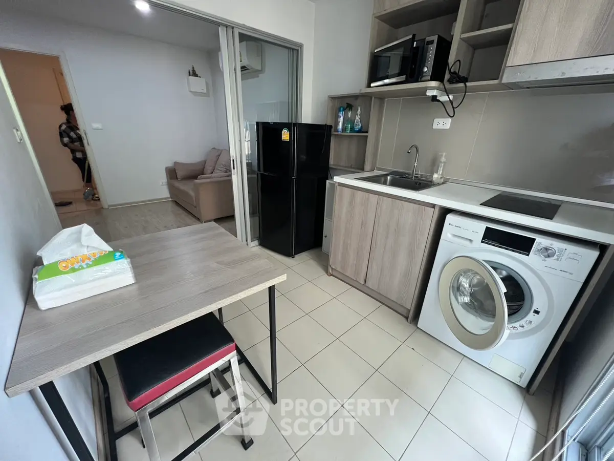 Modern compact kitchen with washing machine and dining area in cozy apartment.