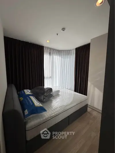 Cozy bedroom with large windows and modern furnishings in a stylish apartment.