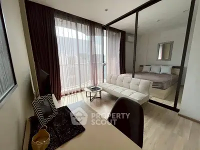 Modern studio apartment with glass partition, cozy bed, and stylish workspace.
