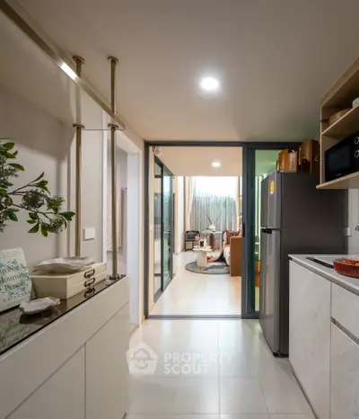 Modern kitchen with open layout leading to a cozy living room, featuring sleek appliances and stylish decor.